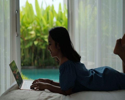 person working on a laptop beside a bright window in Indonesia